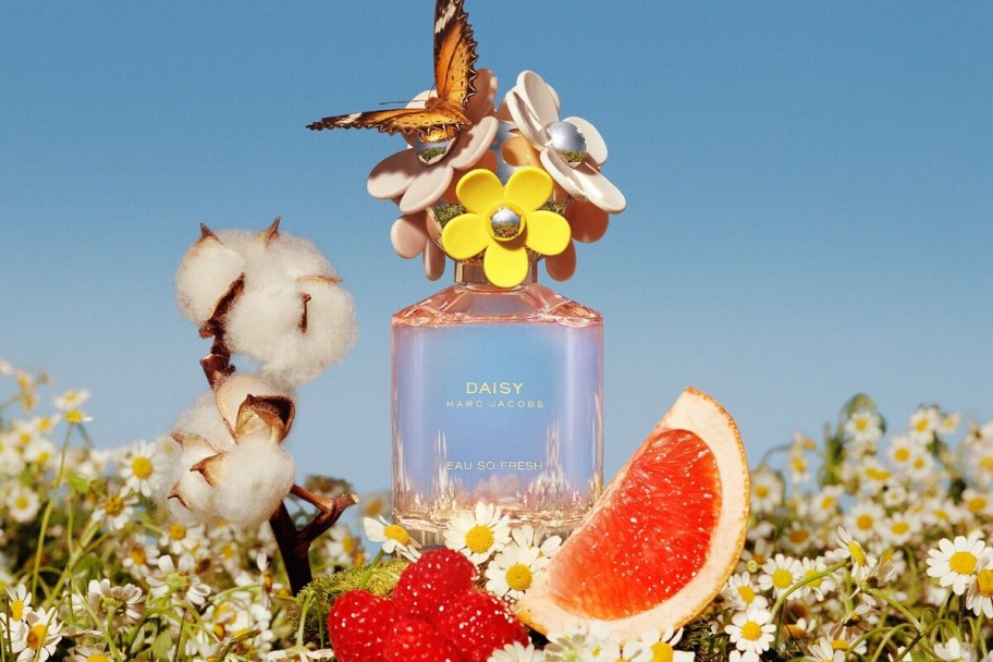 butterfly on top of marc jacobs daisy perfume surrounded by fruit and flowers