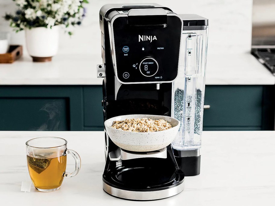 ninja dualbrew coffee maker with cereal bowl and cup of tea next to it