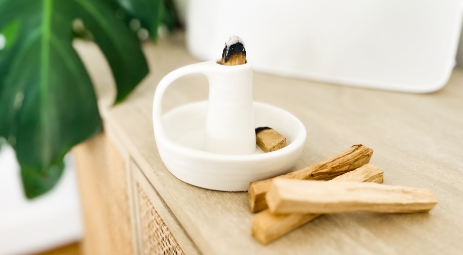 palo santo sticks next to white dish on wood table