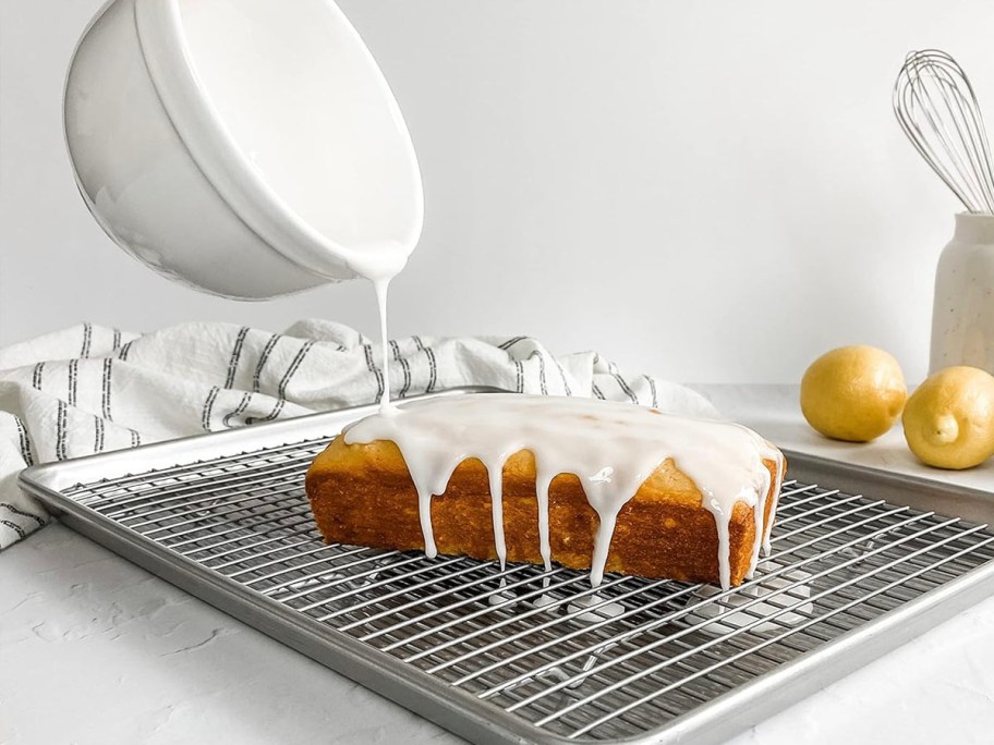 bowl pouring icing on cake on baking tray