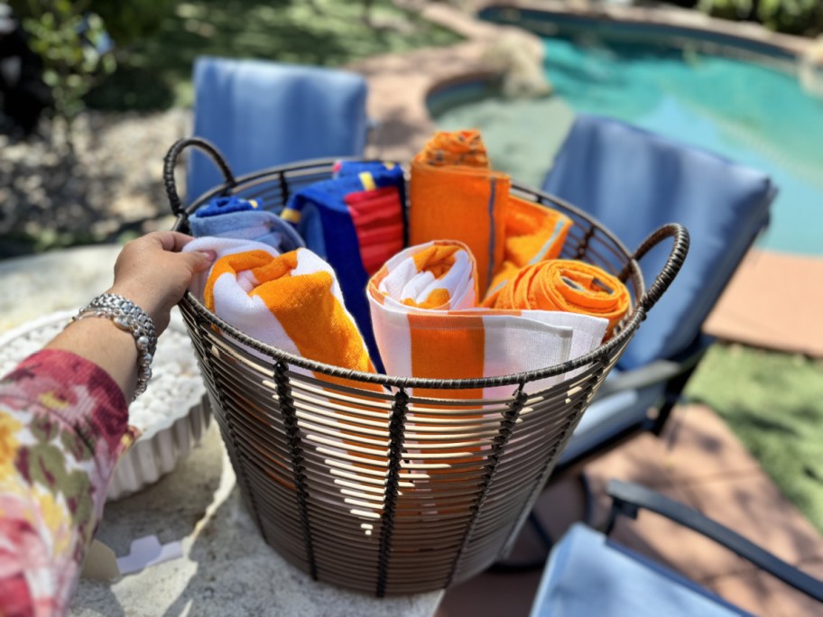 hand touching one of the beach towels gathered into a large walmart storage basket