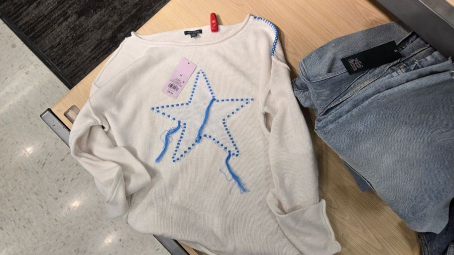 a white sweater with blue star graphic on the front