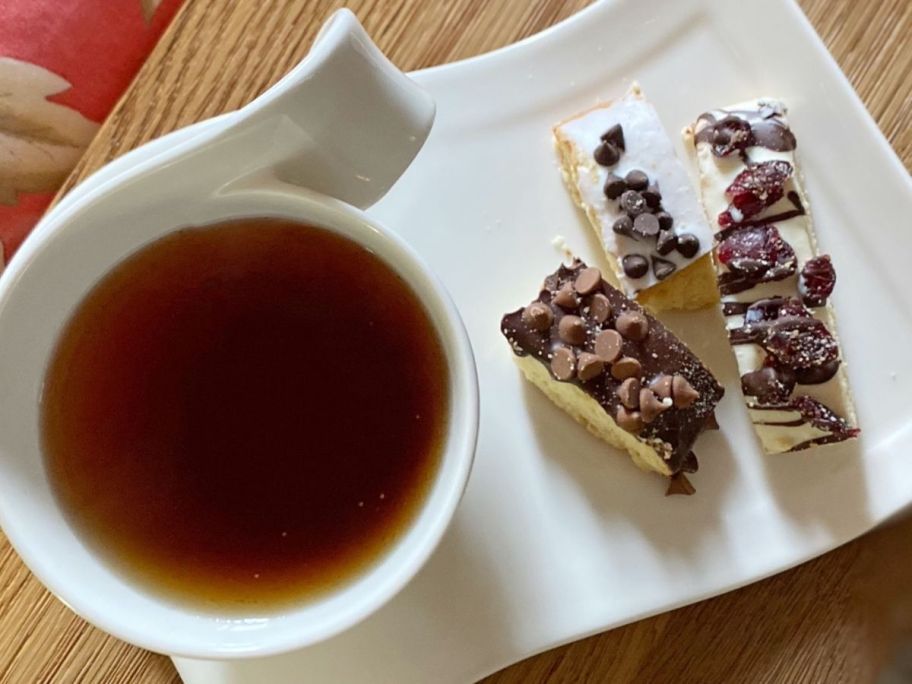 A cup of tea next to a few pieces of Barnett's Biscotti on a plate