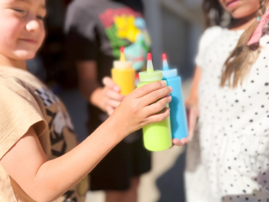 kids cheersing squirt bottles with DIY paint