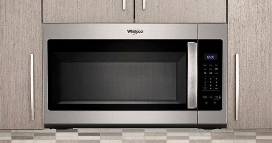 stainless steel microwave above a stove inbetween cabinets