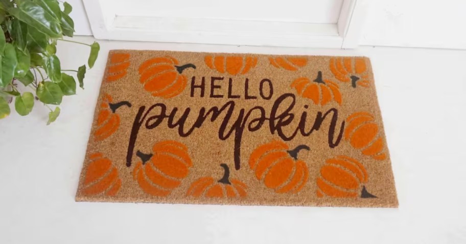 white front door with brown coir doormat with orange pumpkins that says "Hello there pumpkin"