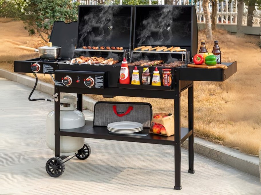 a black propane grill with food cooking on it, sitting on a back patio