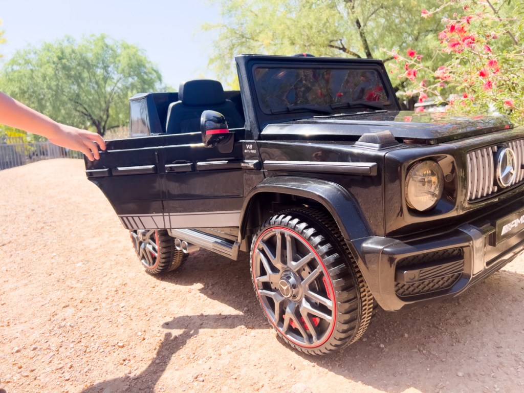 kid opening door of black g wagon ride on car