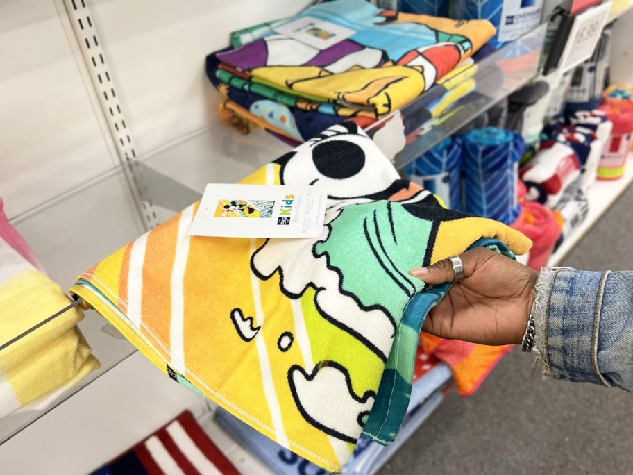 hand grabbing mickey mouse beach towel from store shelf