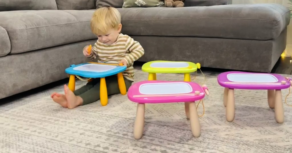 little boy drawing on magnetic board table in living room