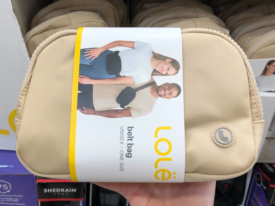 hand holding up a tan belt bag