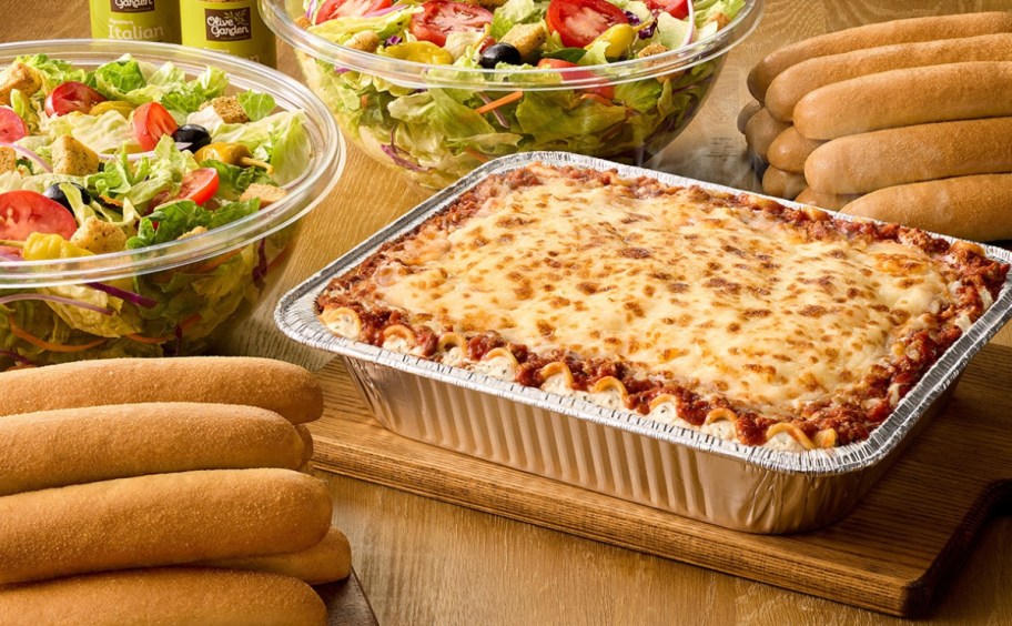 pan of lasagna next to salad and breadsticks