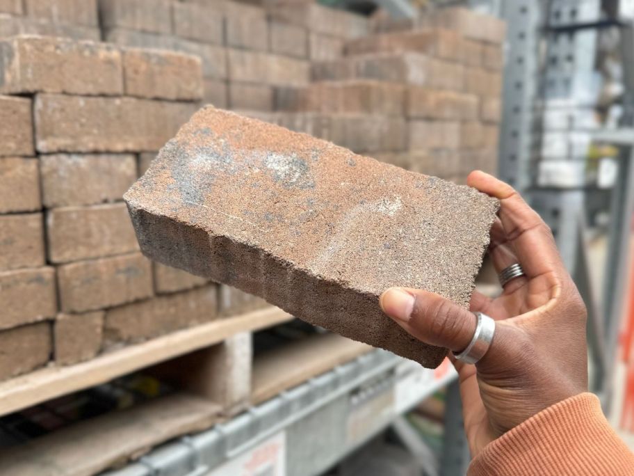 hand holding up a paver stone