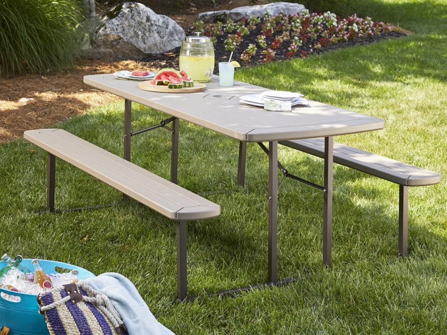 plastic picnic table in grass with sliced watermelon on top