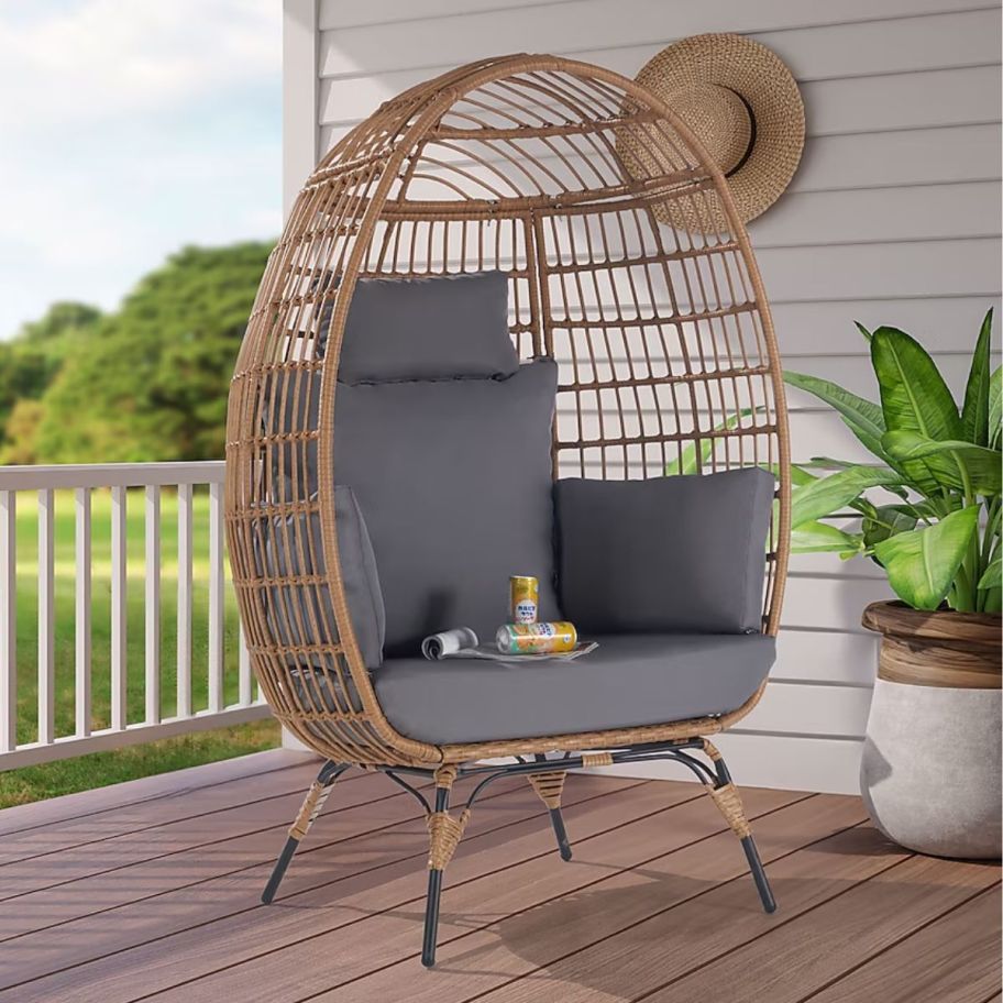 a brown wicker egg chair with gray cushions on a porch