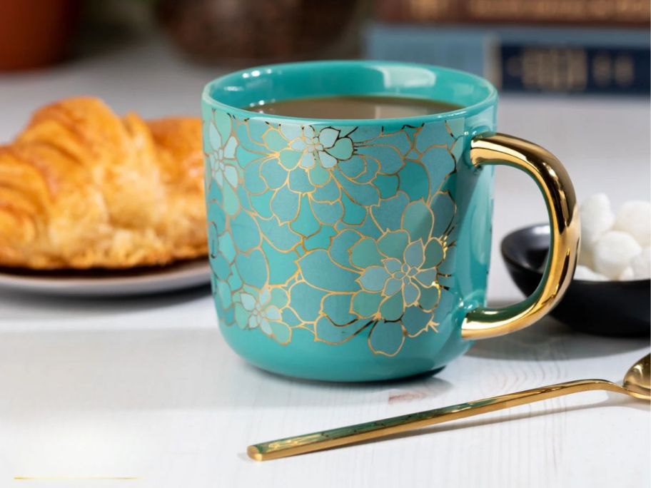 a teal colored succulent print coffee mug on a kitchen counter