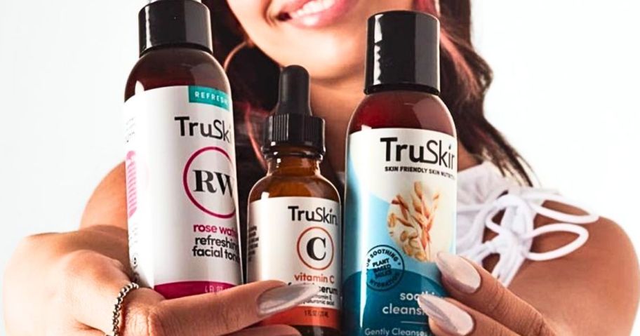 woman holding up 3 bottles of TruSkin skincare items