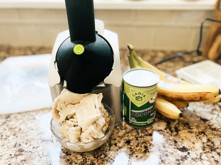 Yonanas frozen treat maker, bowl of soft serve, coconut milk, and bananas on kitchen counter