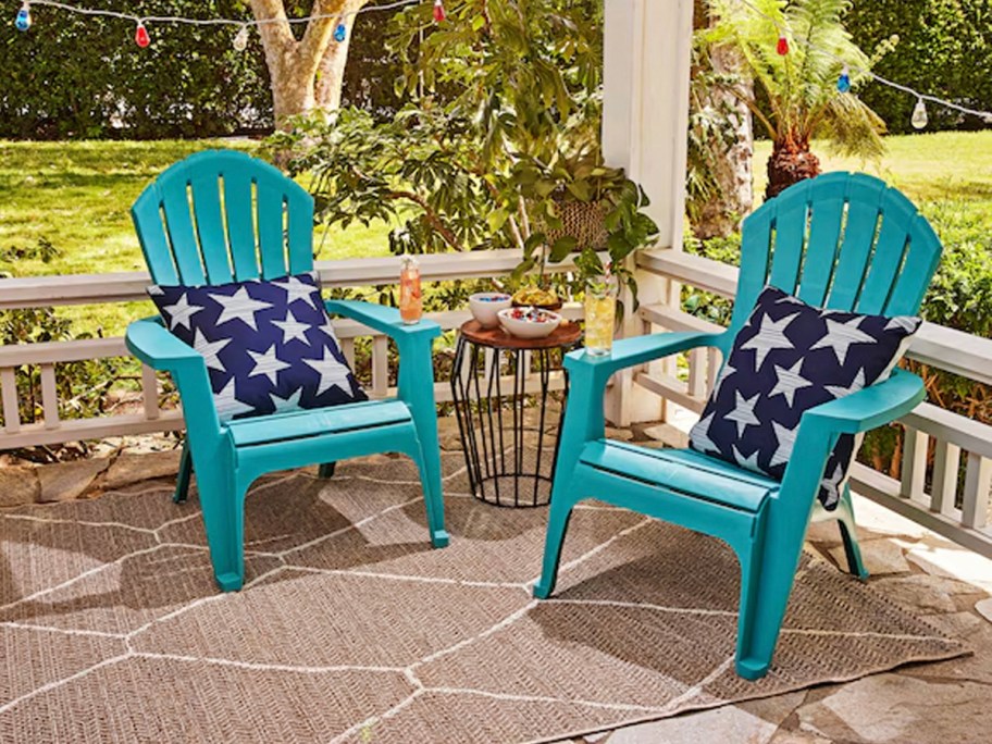 two teal adirondack chairs with pillows on patio 