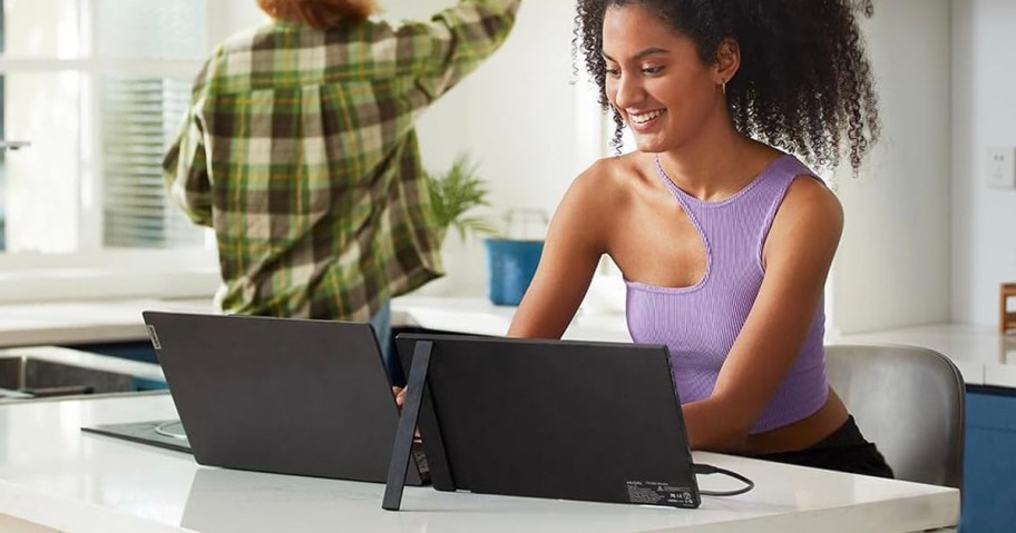 woman typing on laptop with portable monitor next to it