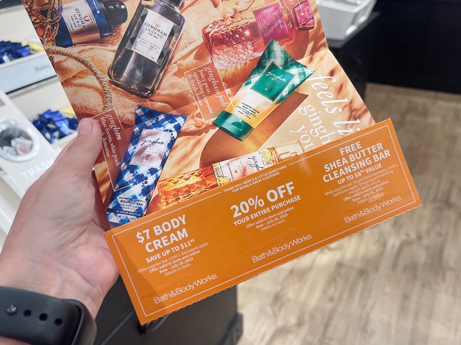 hand holding summer bath and body works mailer with coupons 