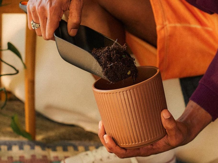 hand using Fiskars Soil Scoop to put dirt into pot