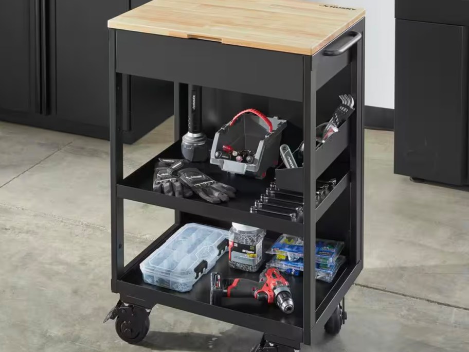 black husky workbench on wheels with wooden top in garage full of tools