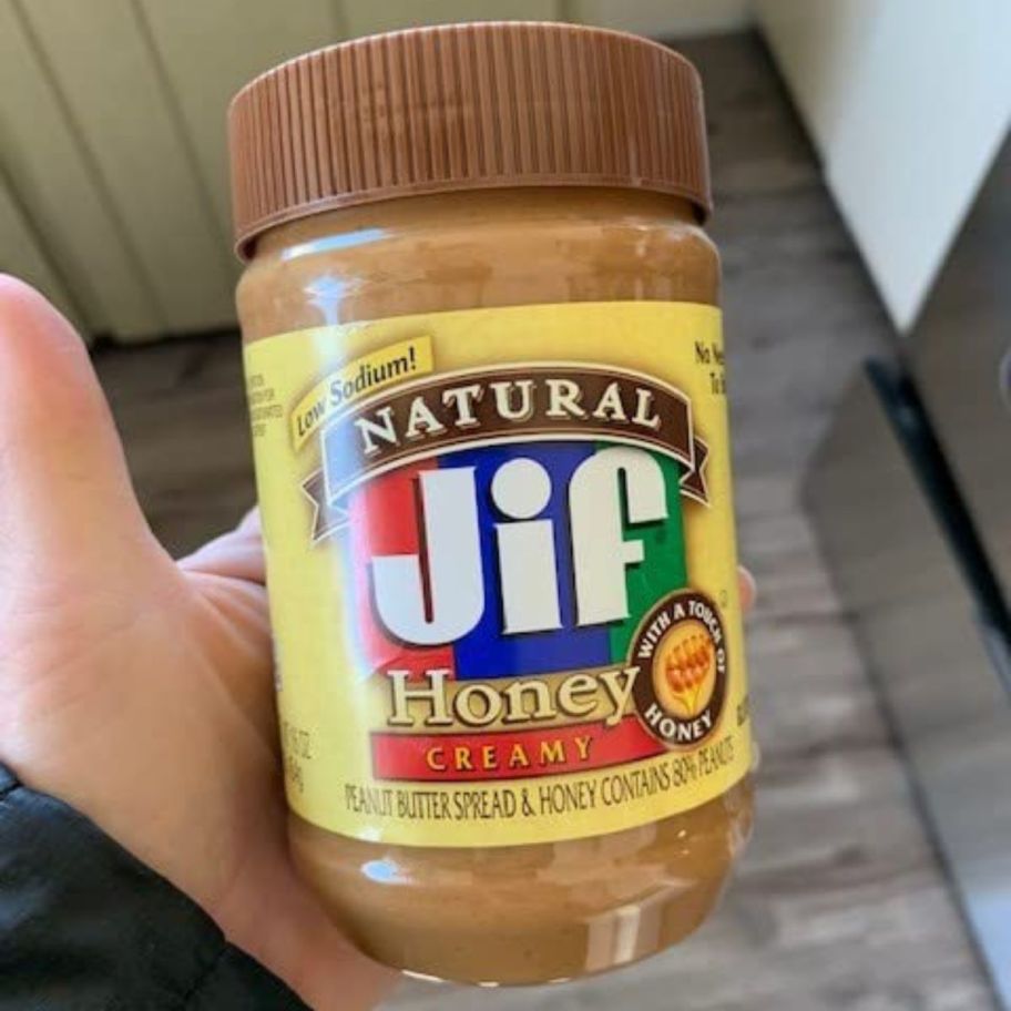 holding a jar of JIF peanut butter with honey