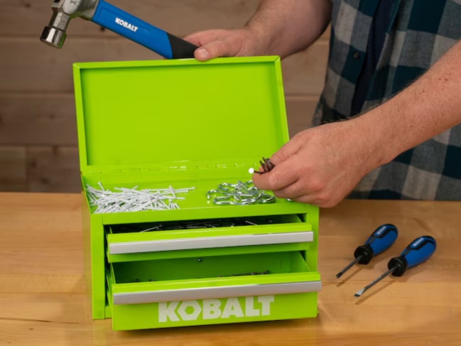 person putting nails into an open bright green Kobalt mini toolbox