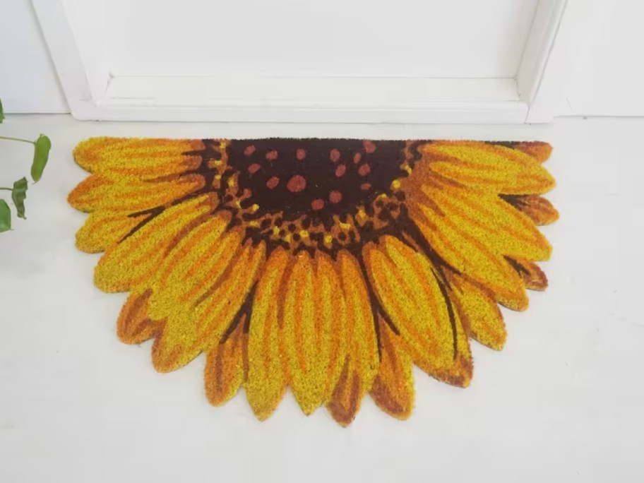 half sunflower shaped coir doormat in front of a white door