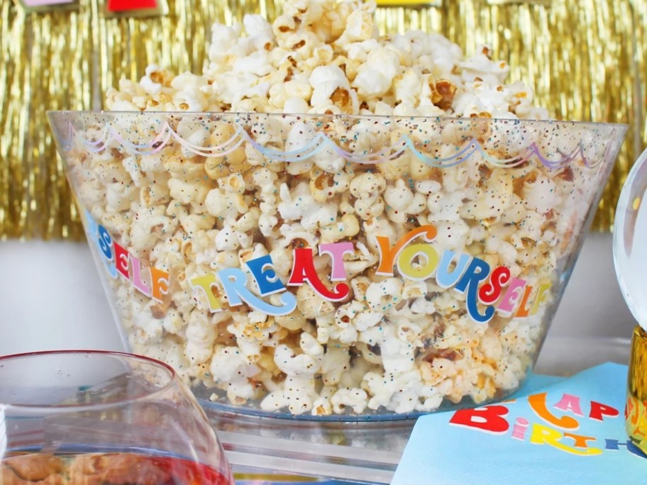 clear glitter bowl that says "Treat Yourself" filled with popcorn