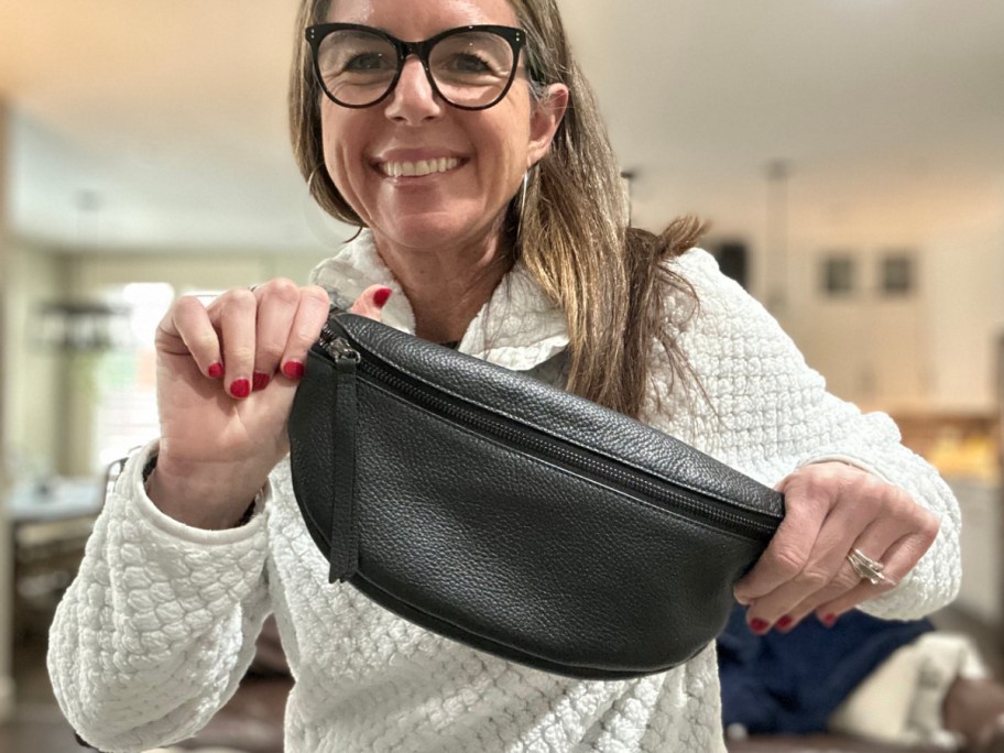 woman holding up black leather sling bag