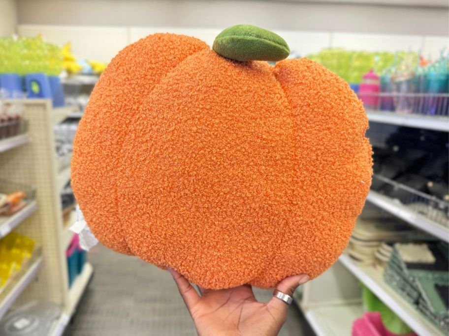 a womans hand holding a medium sized sherpa fabric pumpkin