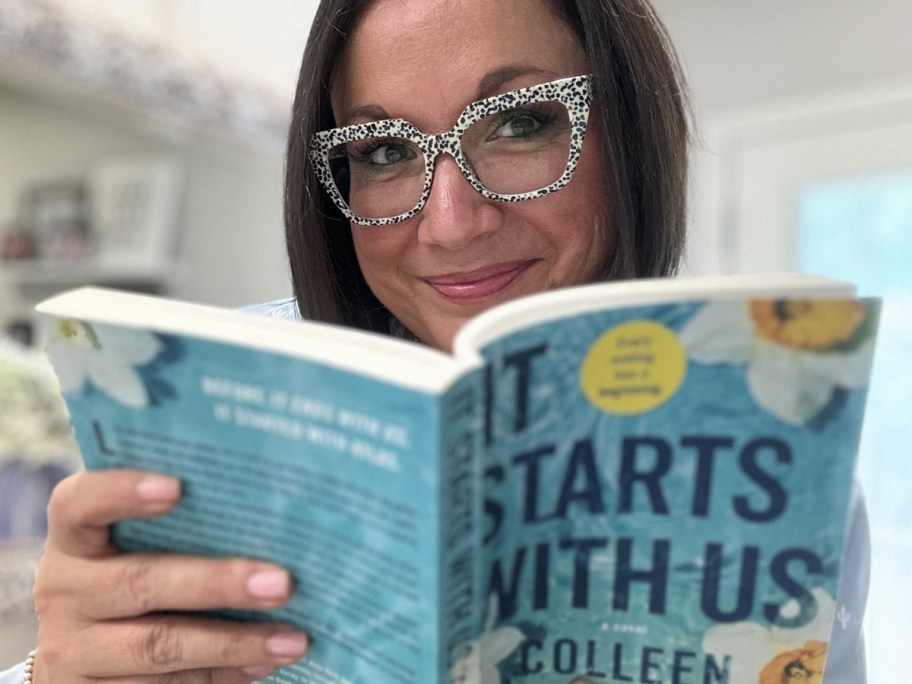 smiling woman wearing Kits glasses while reading book