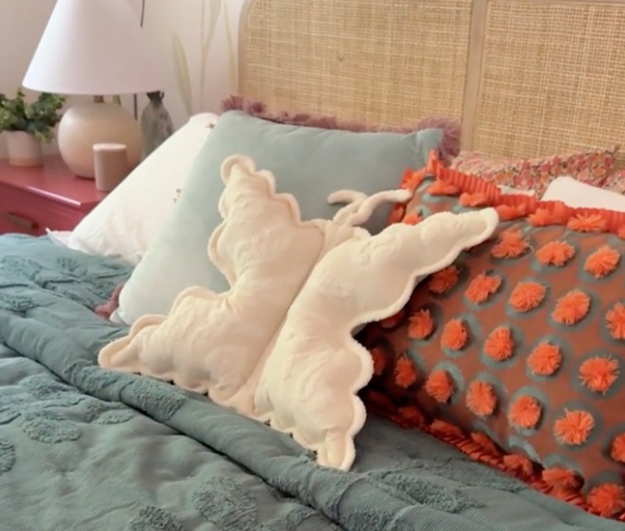 white butterfly pillow on bed with blue tufted quilt