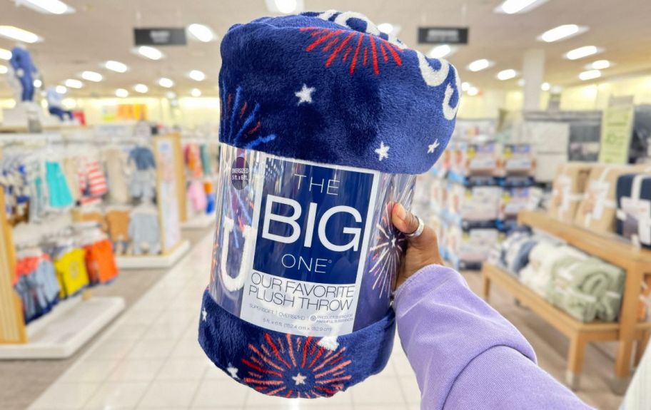 a womans hand holding a dark blue throw with fireworks and USA printed on it