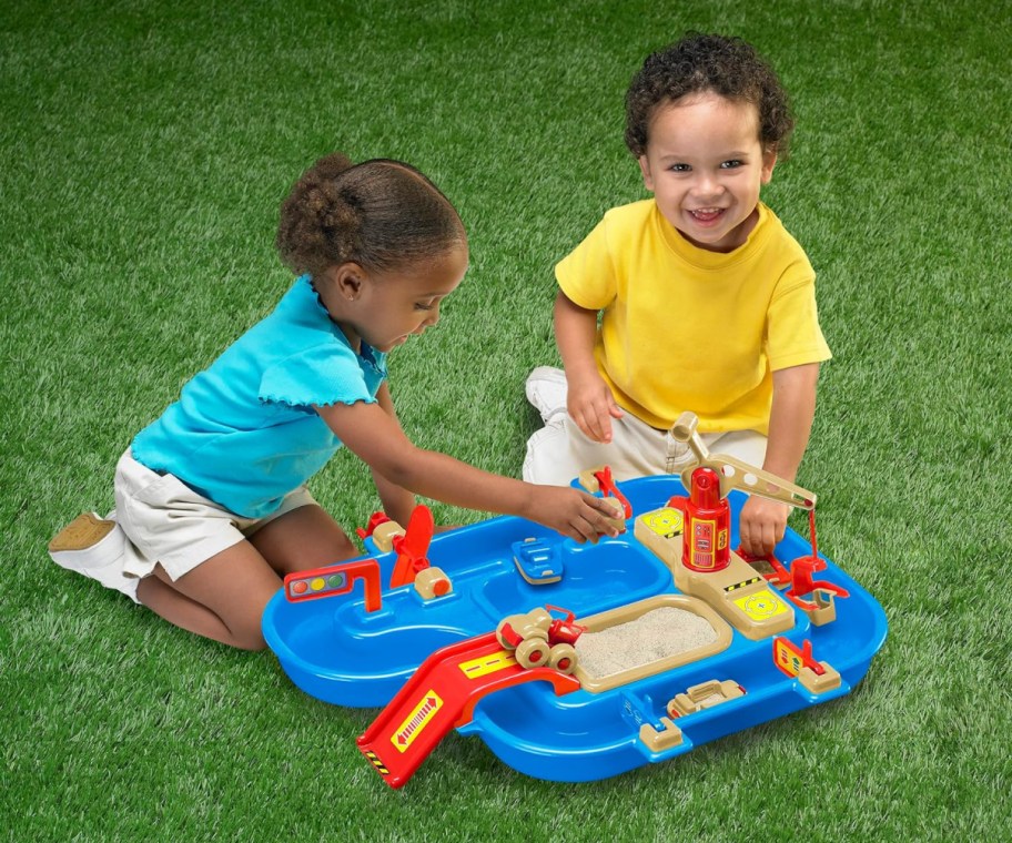 two kids playing with water tabel on grass