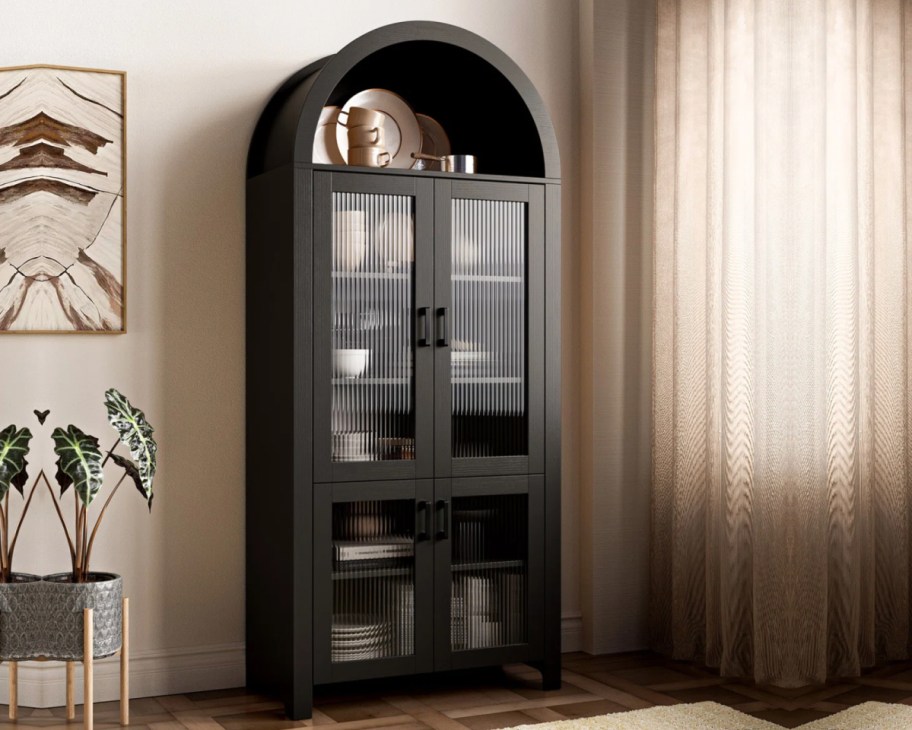 black arched cabinet next to window