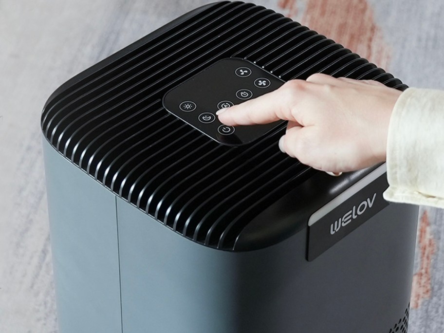 hand pushing buttons on air purifier