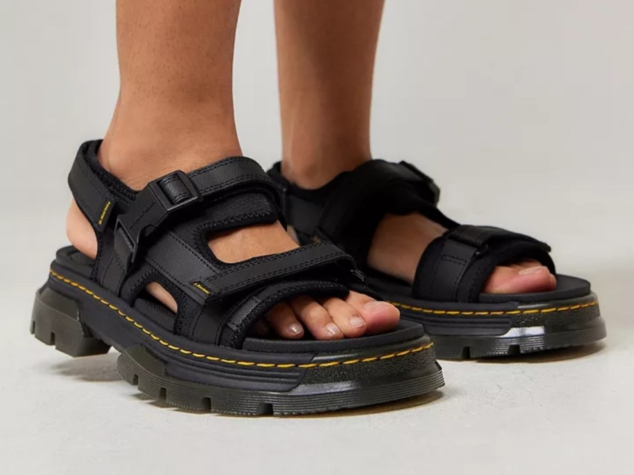 women's feet wearing black Dr. Martens sandals