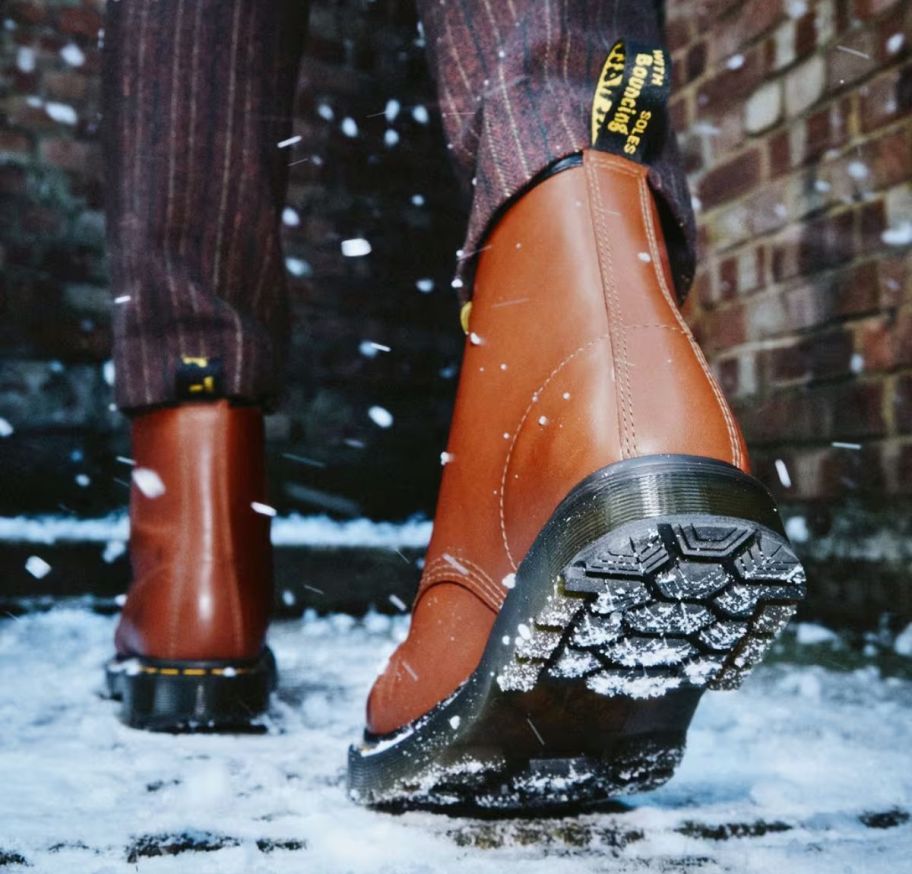 a model wearing a pair of brown leather dr. martens boots