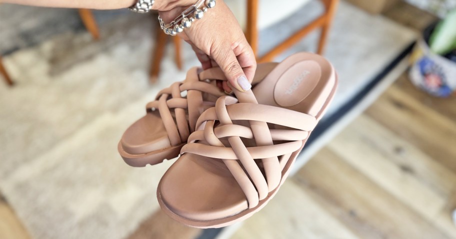 hand holding up a pair of pink woven slides