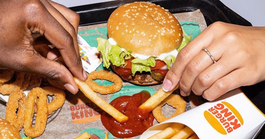 people's hands dipping fries into ketchup on a Burger King food tray with a whopper jr burger and more fries on it