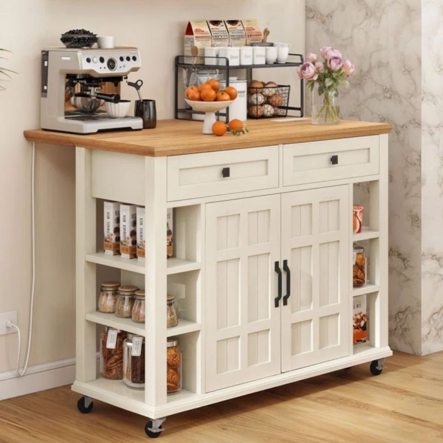 an ivory colored rolling kitchen cart shown with coffee bar items