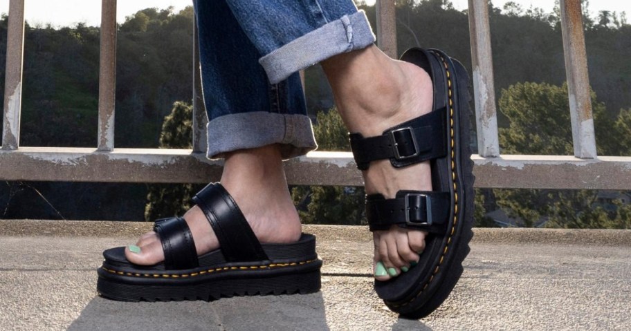 women's feet wearing black double buckle Dr. Martens sandals