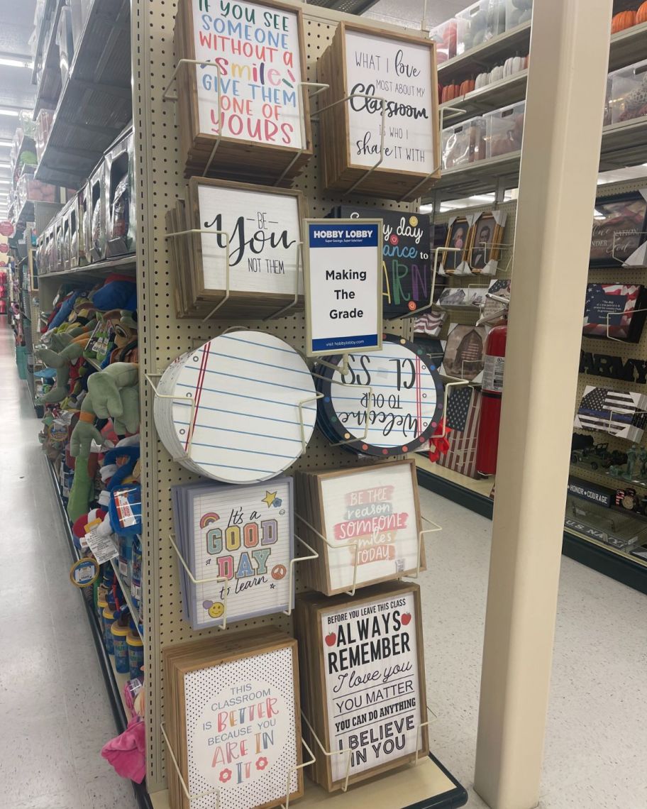 various wooden classroom wall art on an endcap in a store