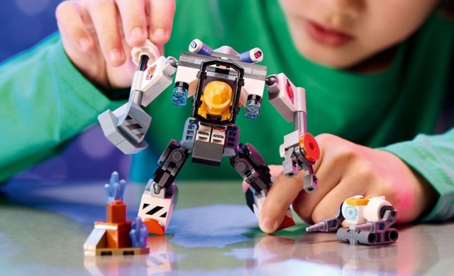 a little boy playing with the lego space construction mech suit building set