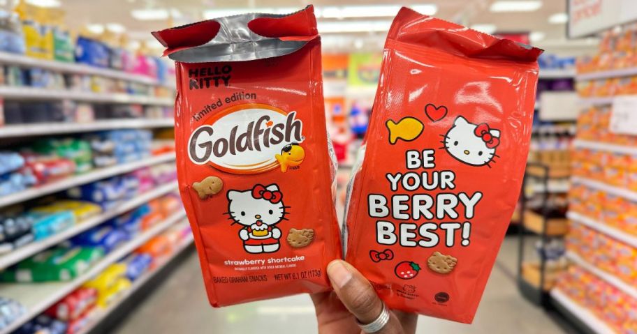 A hand holding up 2 bags of Limited Edition Goldfish Hello Kitty Strawberry Shortcake Grahams