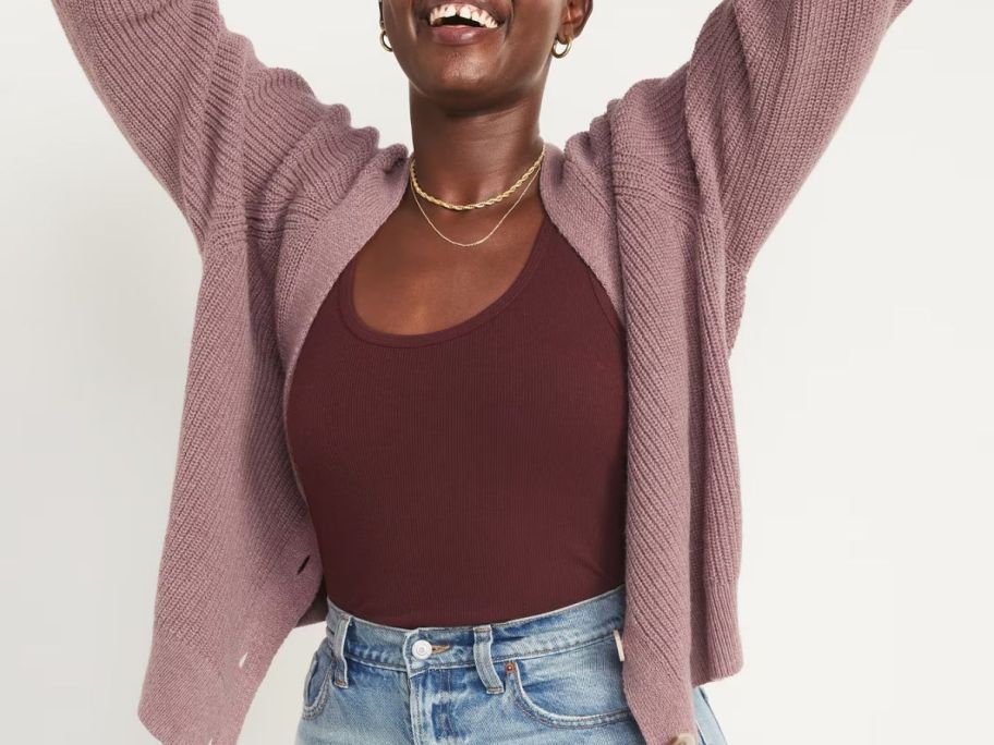 A woman lifting her hands because she loves her Old Navy tank top and pink sweater