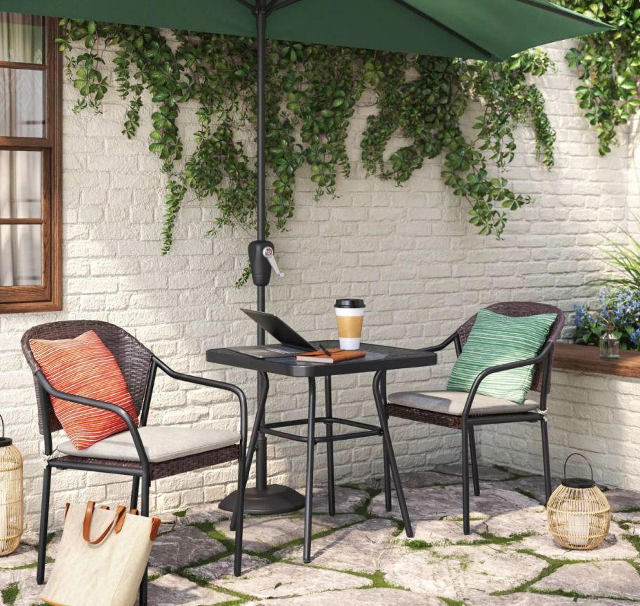 a 3 oiece bistro set on a patio shown with an umbrella